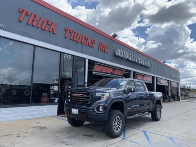 A gmc sierra parked in front of a truck shop.